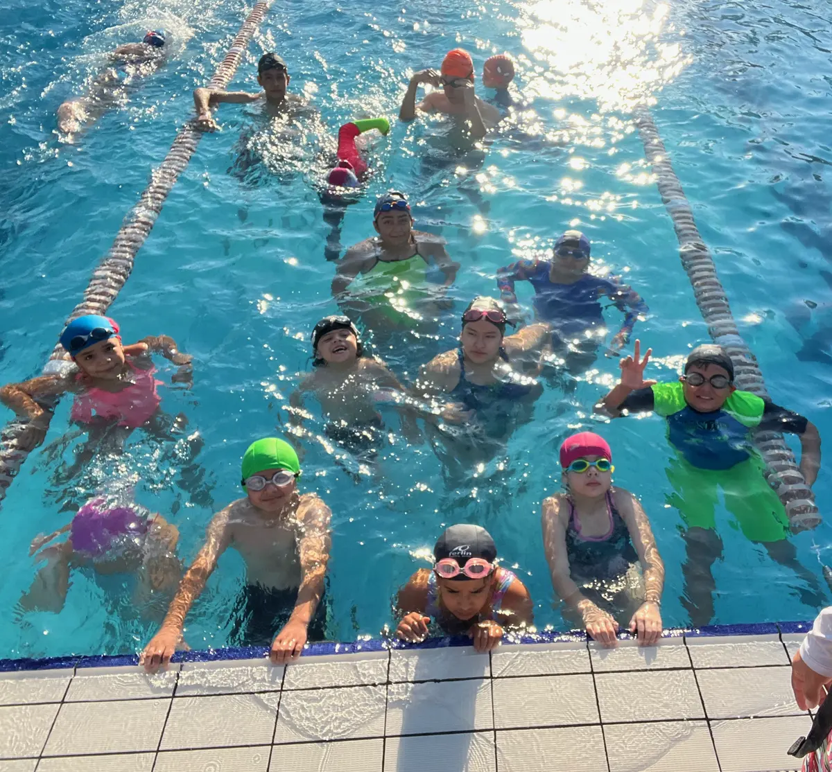 Grupo de niños de una clase de natación sonriendo desde la orilla de la alberca